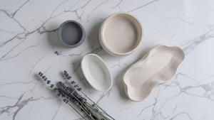 Set of concrete bowls on a marble surface with lavender flowers.