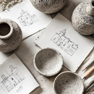 Speckled concrete bowls and vases on architectural drawings with a neutral background