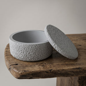 Astral Nock Jar by Lunarie featuring a textured white finish and matching lid, ideal as a decorative storage jar for jewelry and home essentials. Textured grey concrete container with lid on a wooden surface