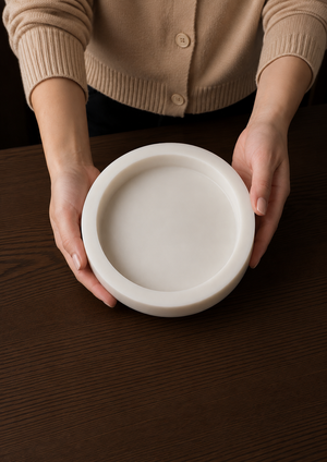 Person holding a white concrete dish on a wooden surface