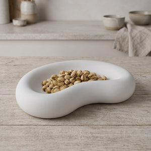 Crescent Dish by Lunarie featuring a smooth crescent moon-inspired shape and matte finish, ideal as a jewelry catchall dish and decorative home accent. place it  with pistachios on a wooden surface