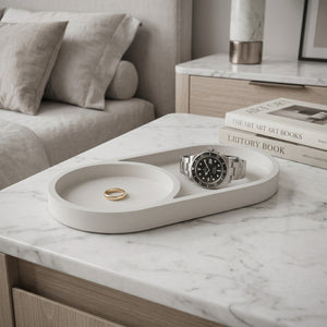Eclipse Orbit Tray by Lunarie featuring a minimalist dual-circle design, ideal as a decorative catchall tray for jewelry and modern home décor. Watch and ring on a tray with books in the background on a marble surface.