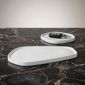 Moon Layers Duo by Lunarie featuring two nesting decorative trays with organic shapes, ideal for jewelry, candles, and modern home décor. Two white trays on a black marble surface with a key on one of them.