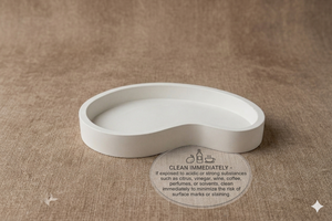 White concrete dish on a brown fabric background with cleaning instructions.