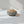 Moonstone Hollow Bowl by Lunarie featuring a moon-inspired textured surface and organic sculptural design for modern home décor.  place it with Pistachios in a gray concrete bowl on a white surface with soft shadows