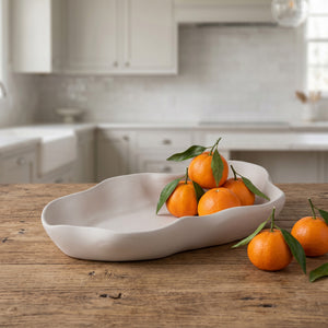 Nest Centerpiece Bowl by Lunarie featuring an organic sculptural shape with flowing curves, ideal as a decorative centerpiece bowl for modern home décor.   with oranges on a wooden table in a kitchen setting