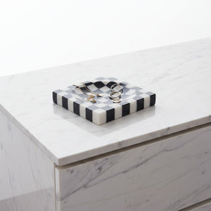 Noir Blanc Checkered Trinket Dish by Lunarie crafted from natural marble with a black and white checkered pattern and wavy sculptural design. place as jewelry dish with rings on a marble surface