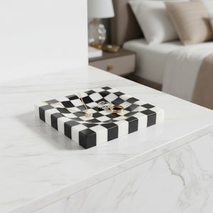 Noir Blanc Checkered Trinket Dish by Lunarie crafted from natural marble with a black and white checkered pattern and wavy sculptural design.  on a marble surface with jewelry, in a bedroom setting.