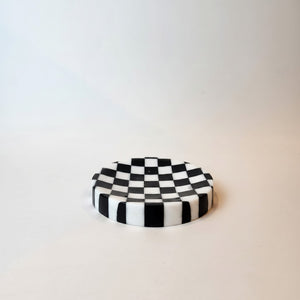 A small round  noir-blanc-checkered-trinket-dish-round-lunarie with a black and white checkerboard pattern, standing upright on a plain light background.