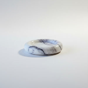 A polished noir blanc large light veins dish photographed on a seamless light gray background.