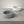 Two  small  orbit  concrete bowls, one gray and one white, on a light gray surface.